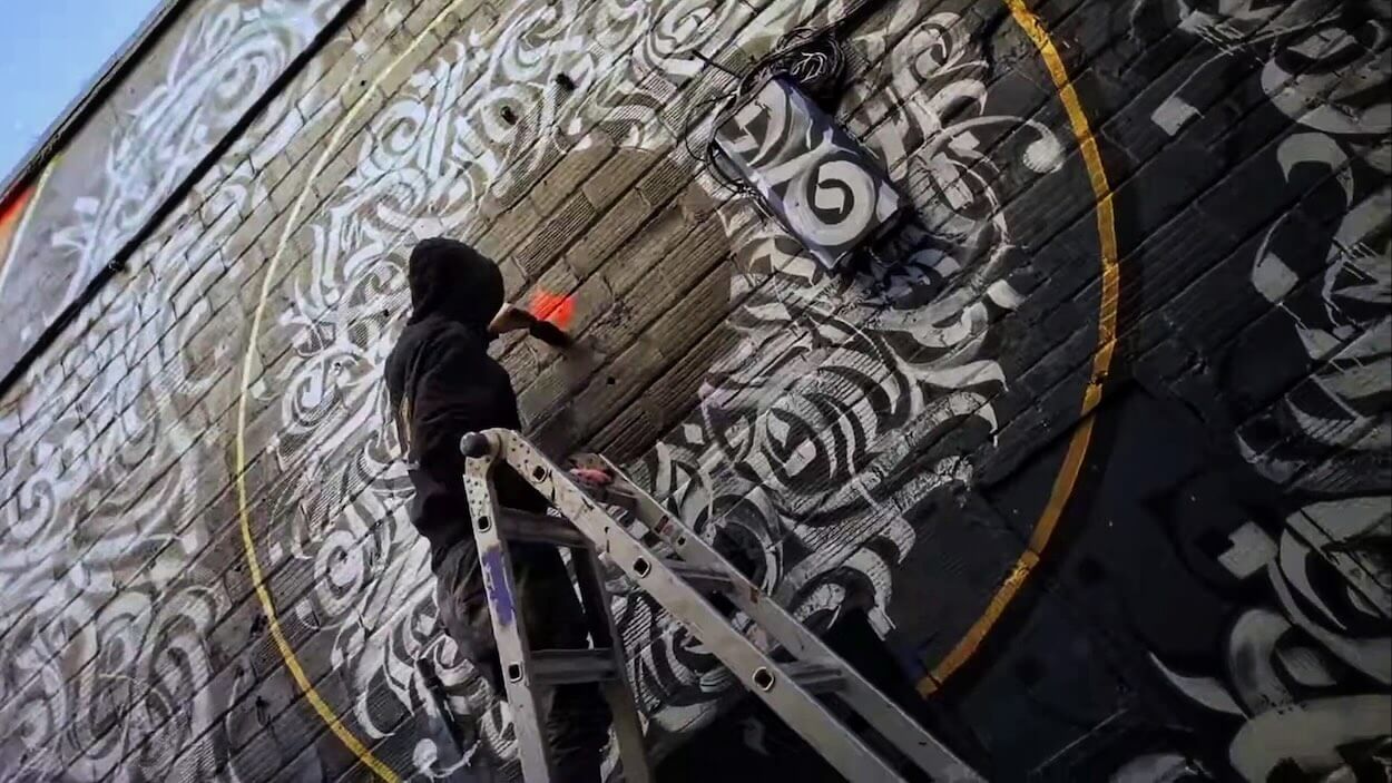 Calligraffiti en cours de réalisation sur un mur