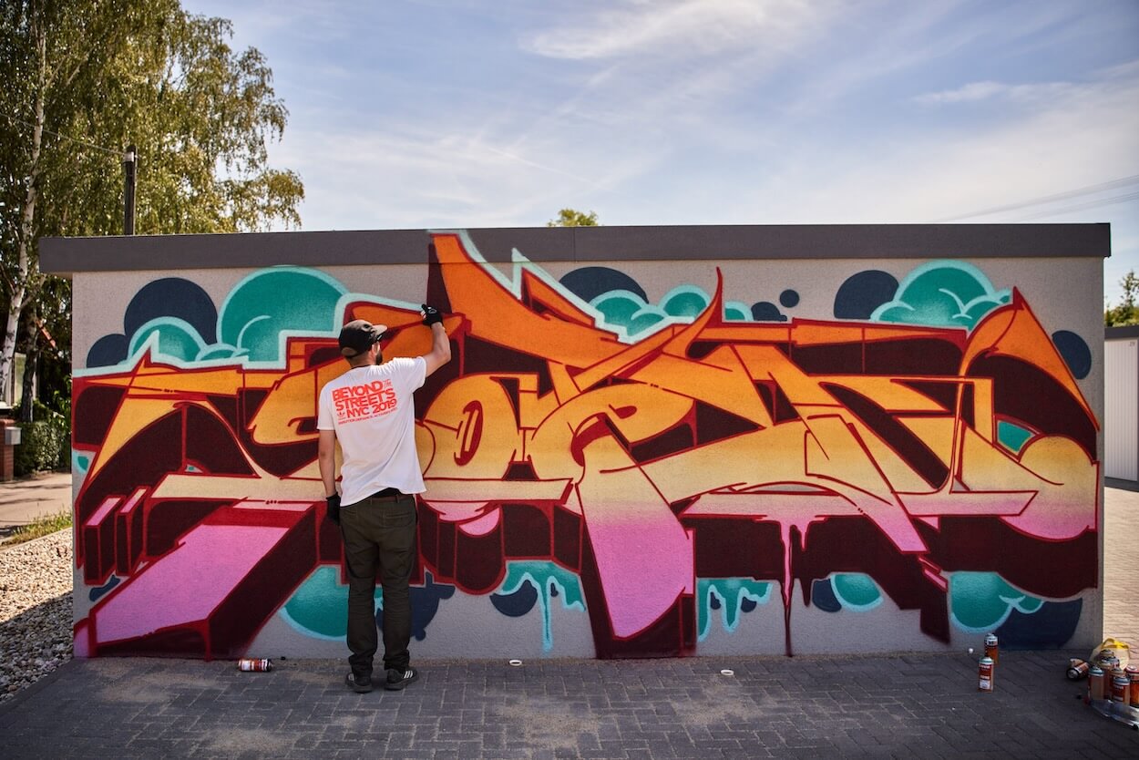 l'artiste graffeur SOTEN au travail sur un lettrage coloré