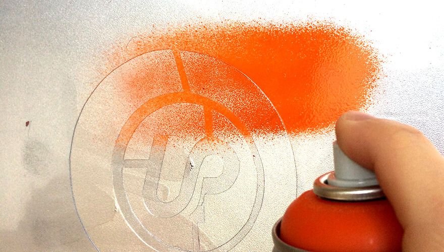 Application de la peinture en bombe sur le pochoir